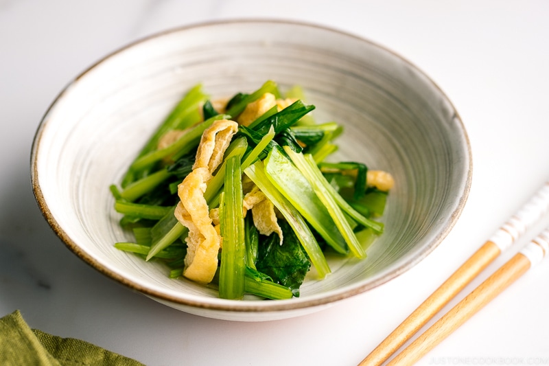 A white Japanese ceramic bowl containing Simmered Fried Tofu and Greens.