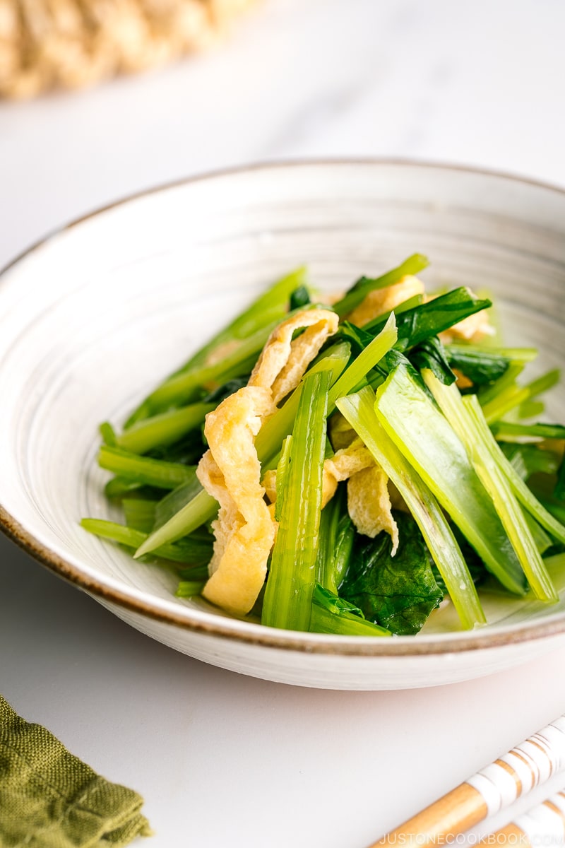 A white Japanese ceramic bowl containing Simmered Fried Tofu and Greens.