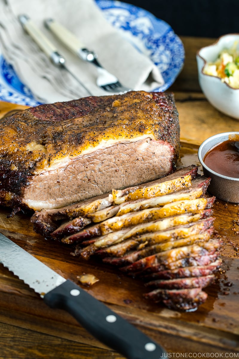 Smoked A5 Japanese wagyu brisket on a wood cutting board next to bbq sauce and potato salad | Easy Japanese Recipes at JustOneCookbook.com