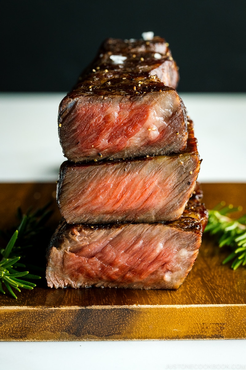 steaks reverse seared to medium rare, medium, and medium well on Traeger stacked on top of wood cutting board