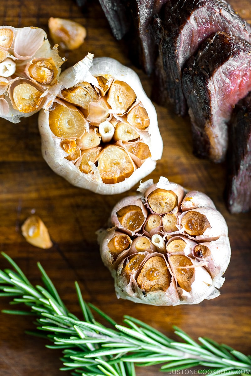 smoked whole garlic next to sliced steak