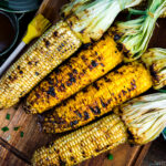 Grilled corn with miso butter sauce on the wooden cutting board.