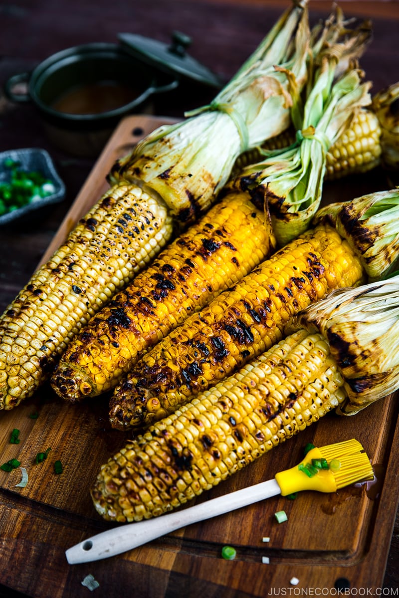 Grilled corn with miso butter sauce on the wooden cutting board.