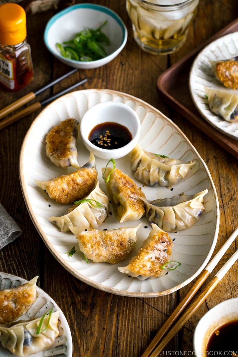A white oval plate containing Vegetable Gyoza and dipping sauce.