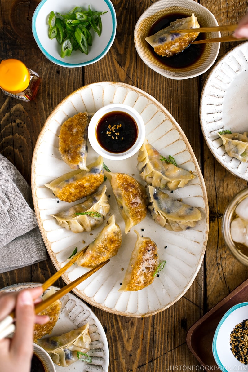 A white oval plate containing Vegetable Gyoza and dipping sauce.