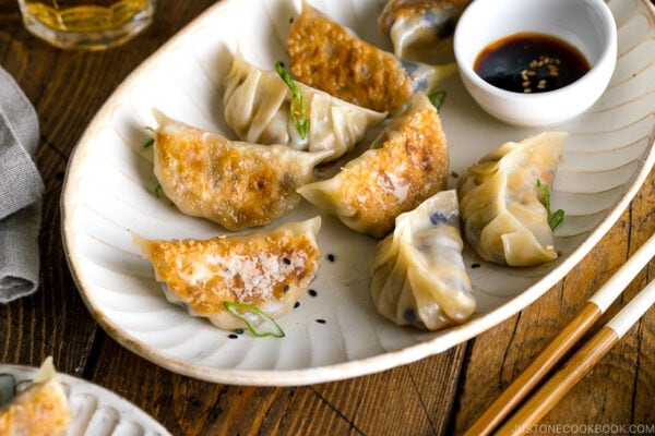 A white oval plate containing Vegetable Gyoza and dipping sauce.