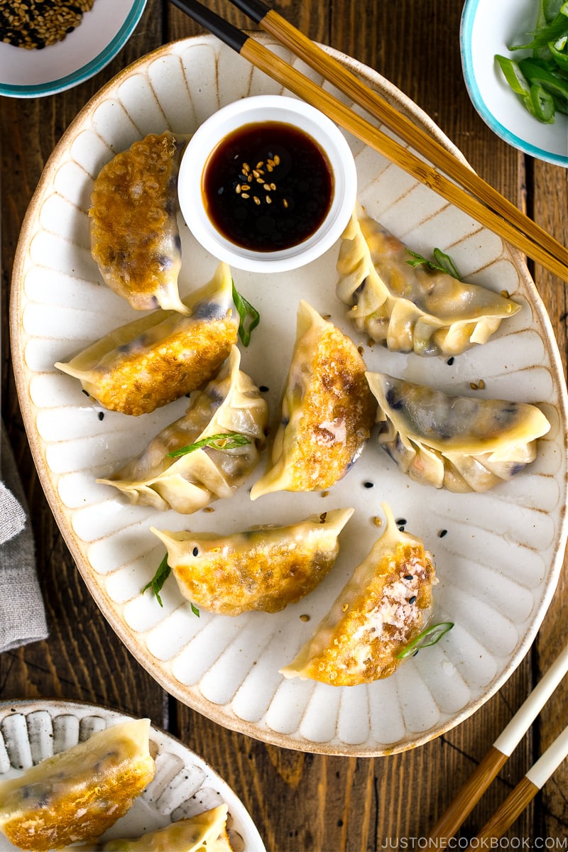 A white oval plate containing Vegetable Gyoza and dipping sauce.