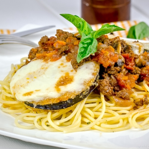 A white plate containing Eggplant Parmesan Spaghetti.