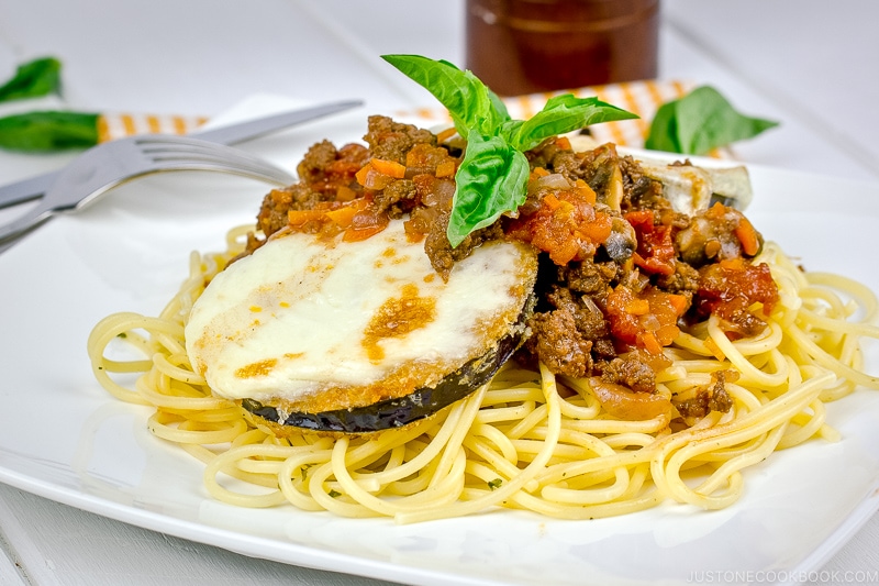 A white plate containing Eggplant Parmesan Spaghetti.