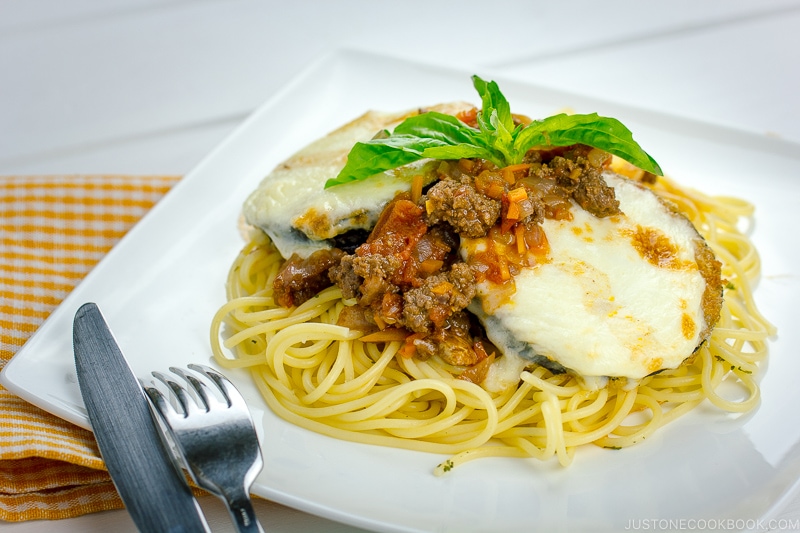 A white plate containing Eggplant Parmesan Spaghetti.