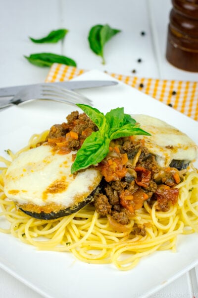 A white plate containing Eggplant Parmesan Spaghetti.