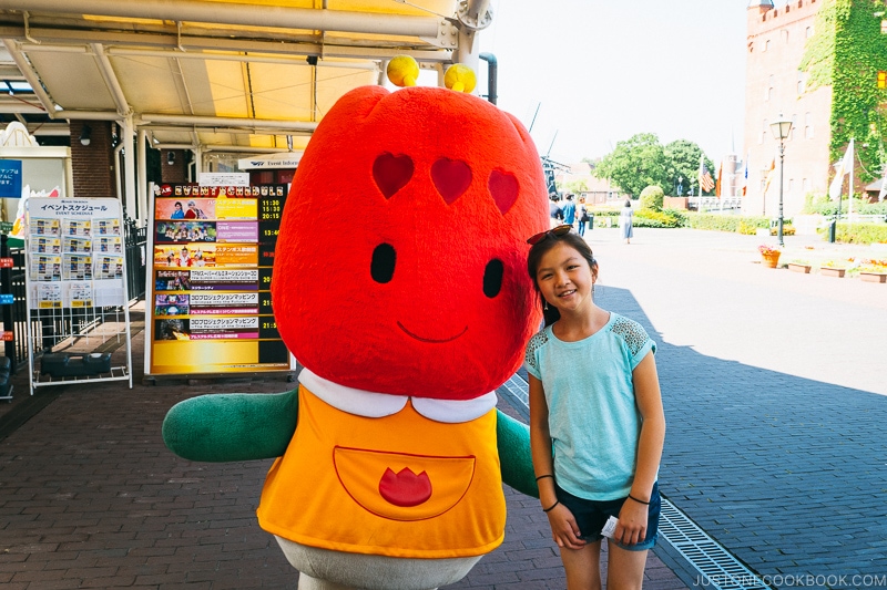 girl standing next to Huis Ten Bosch mascot