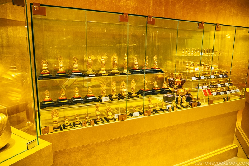 gold buddha statues inside a glass case