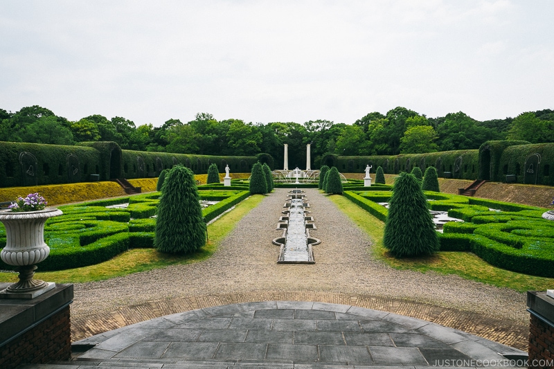 european style garden with hedges and trees and rock walking path