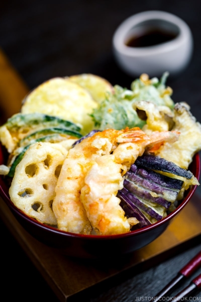 Assorted tempura served on a bed of steamed rice in a red lacquered bowl.