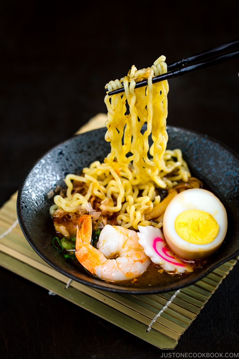 A black bowl of Tsukemen dipping sauce and a white bowl containing noodles with toppings.