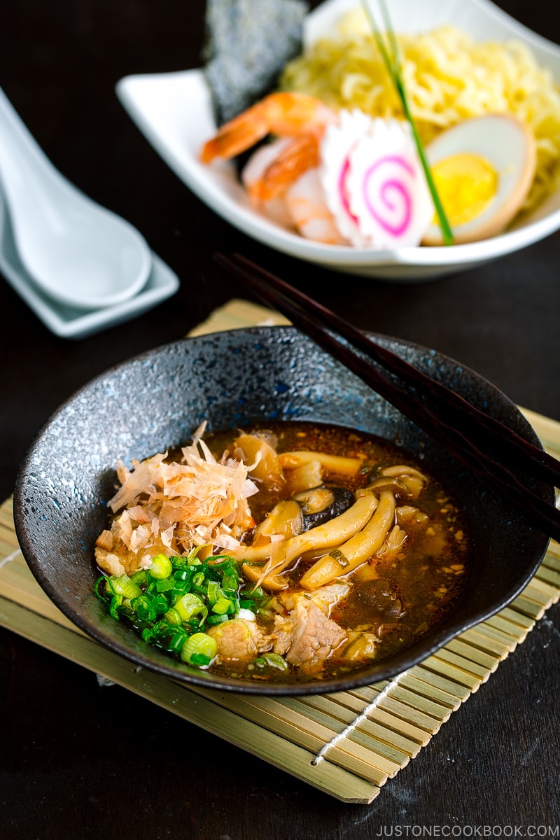 A black bowl of Tsukemen dipping sauce and a white bowl containing noodles with toppings.