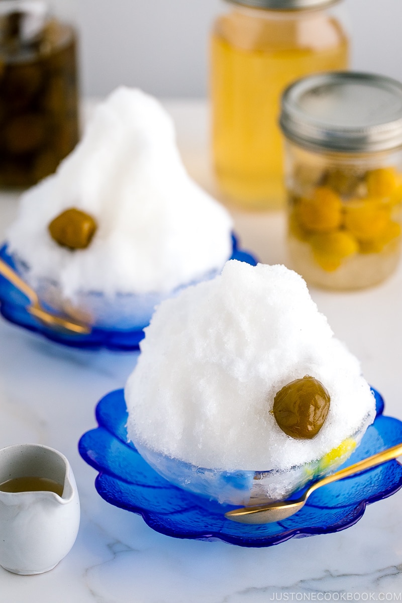 A blue glass bowl containing shaved ice, ume plum syrup, and ume compote.