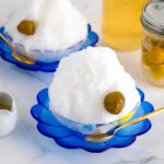 A blue glass bowl containing shaved ice, ume plum syrup, and ume compote.