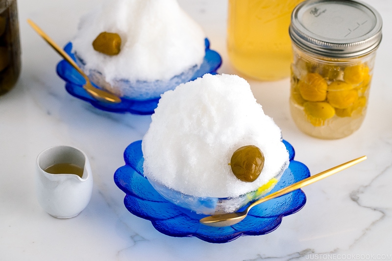 A blue glass bowl containing shaved ice, ume plum syrup, and ume compote.