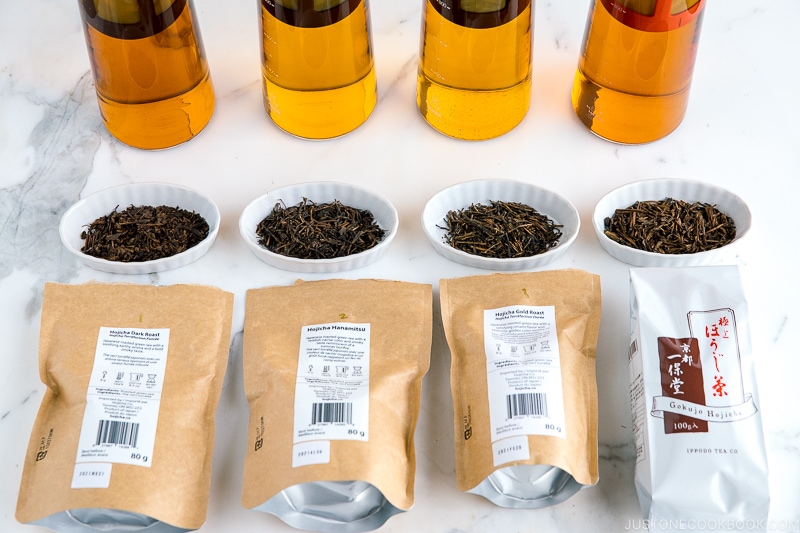 different types of hojicha tea leaves in white dish in front of cold brew hojicha