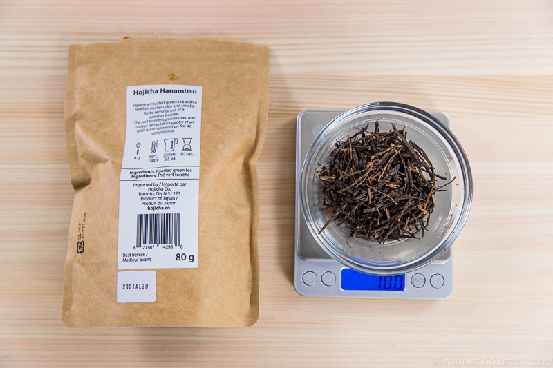 10 grams of hojicha on a scale next to a package on cutting board