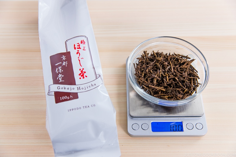 10 grams of hojicha on a scale next to a package on cutting board