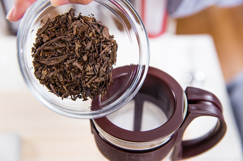 hojicha in a glass bowl pouring into a glass pitcher