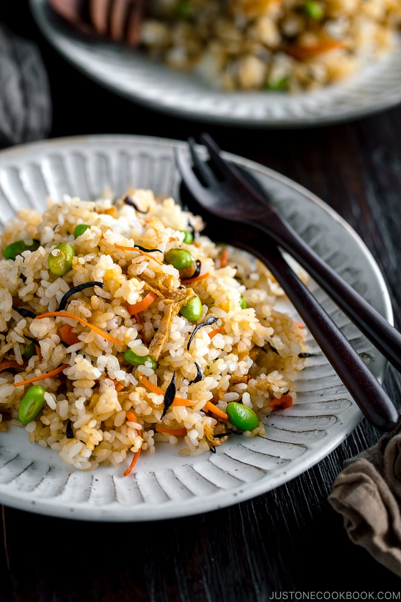 Japanese Fried Rice with Edamame, Tofu and Hijiki Seaweed on a white plate served with wooden utensils.