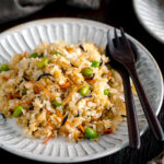 Japanese Fried Rice with Edamame, Tofu and Hijiki Seaweed on a white plate served with wooden utensils.