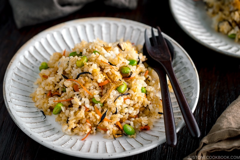 Japanese Fried Rice with Edamame, Tofu and Hijiki Seaweed on a white plate served with wooden utensils.