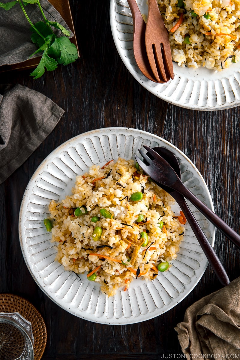 Japanese Fried Rice with Edamame, Tofu and Hijiki Seaweed on a white plate served with wooden utensils.