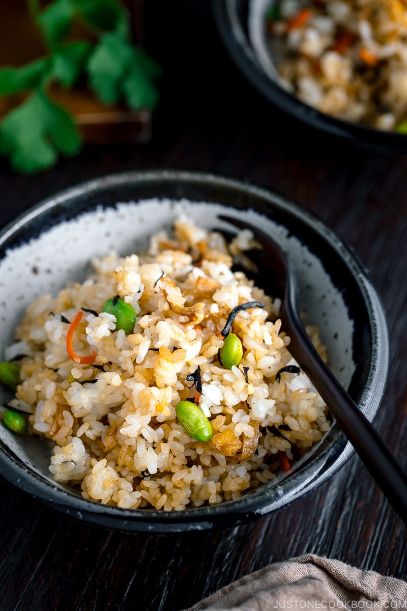 Japanese Fried Rice with Edamame, Tofu and Hijiki Seaweed on a white plate served with wooden utensils.