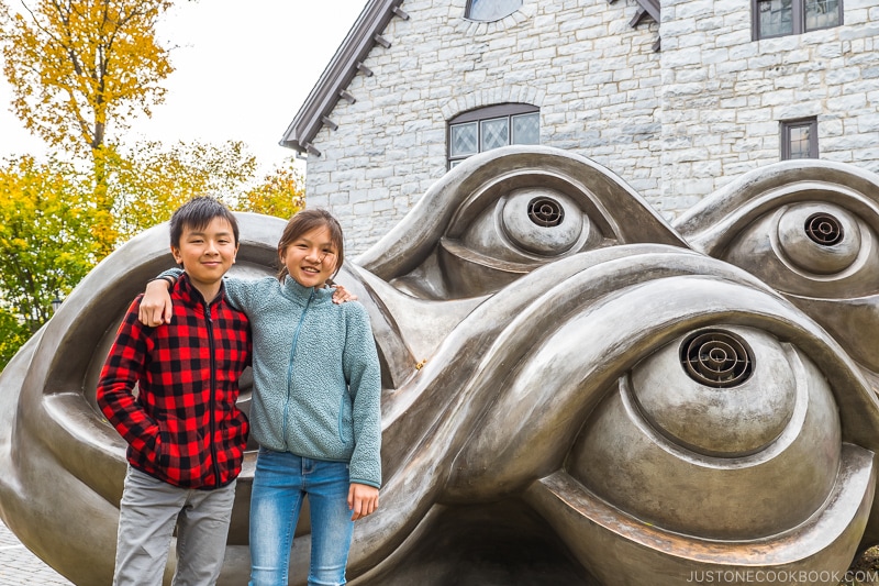 two children standing in front of sculpture of eyes by Louise Bourgeois