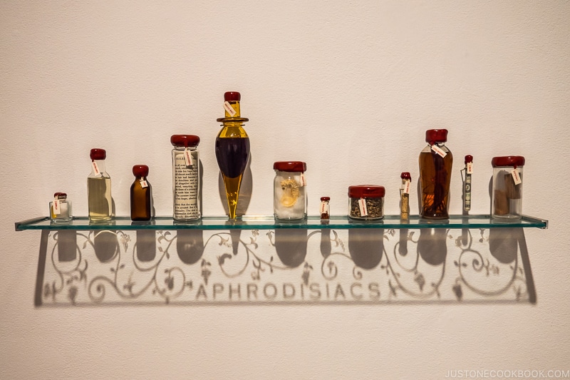 Aphrodisiacs by John Hatfield with bottles on a glass shelf and casting shadows below