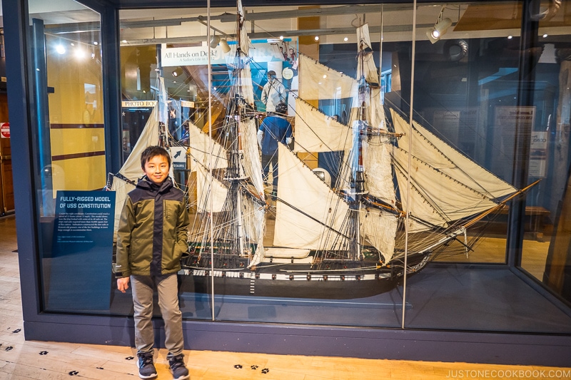 boy standing in front of a fully-rigged model of USS Constitution