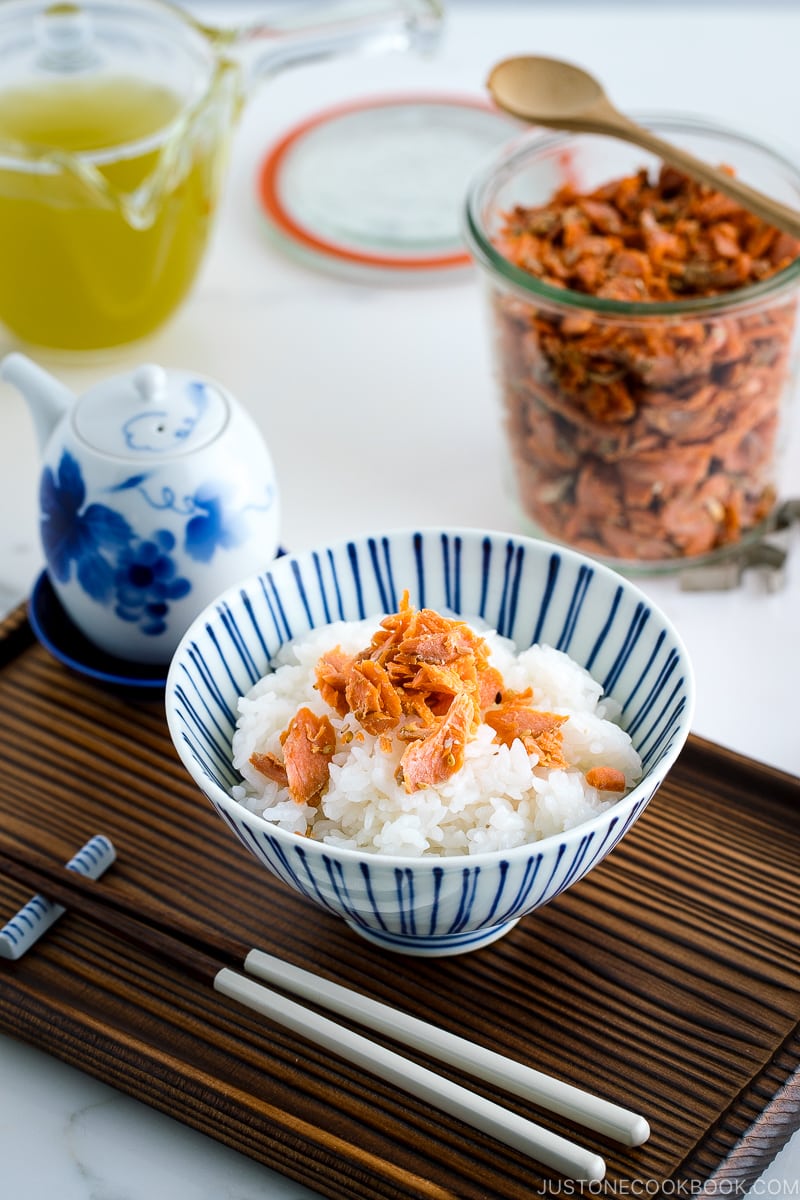 A bowl containing steamed rice topped with salmon flakes.