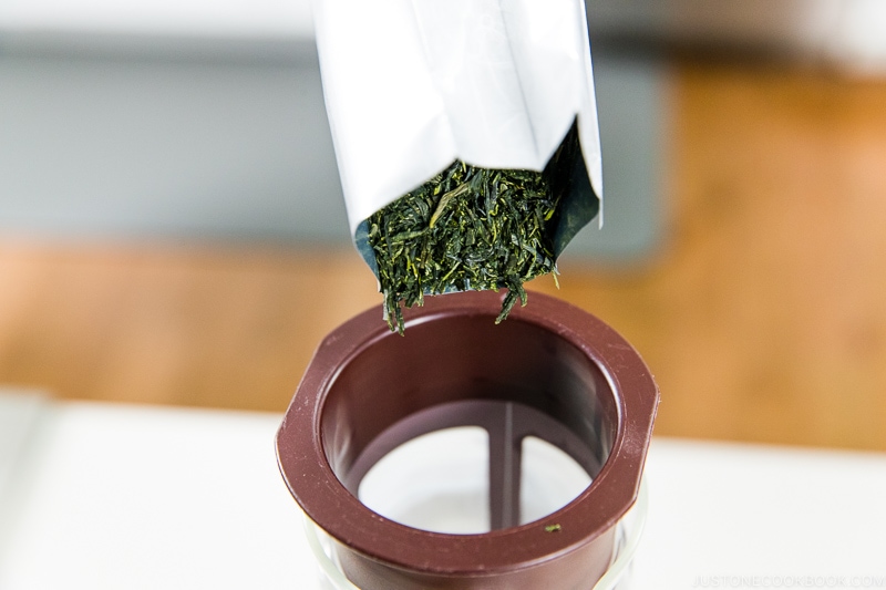 green tea leaves being pour into a cold brew pitcher