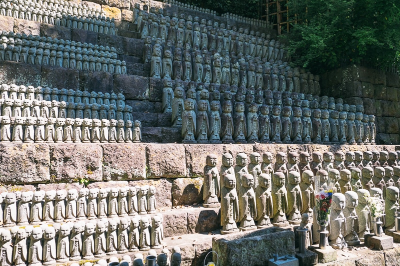 hundreds of stone jizo statues lined up on a hill