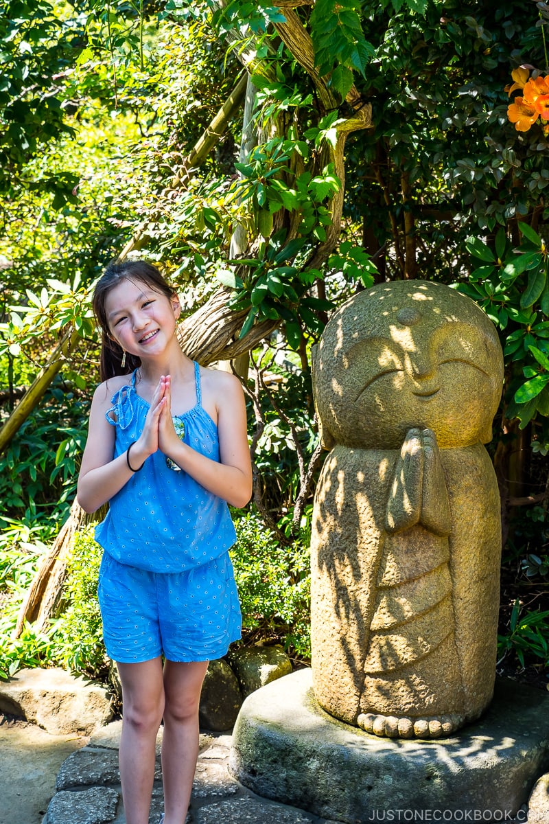 a girl next to a stone jizo statue