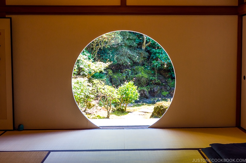 a Japanese room with tatami and a circle cut into a wall looking into a garden