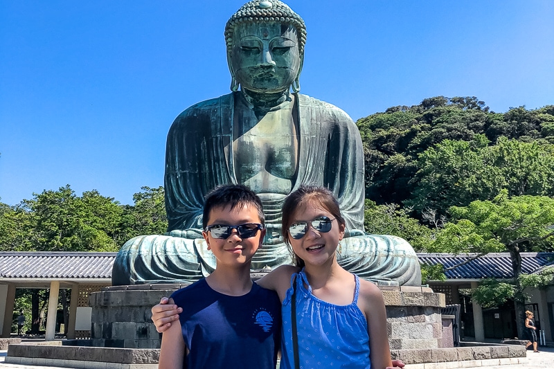 two children in front of giant buddha