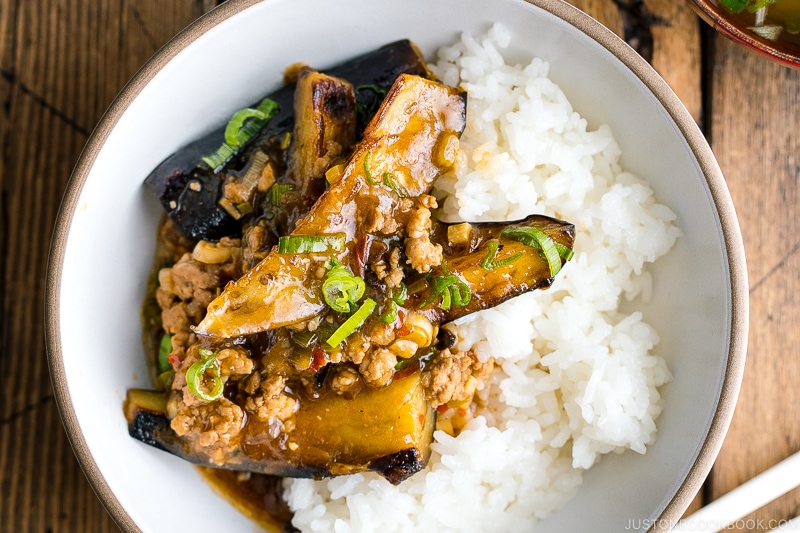 A white bowl containing Mapo Eggplant (Mabo Nasu) served over steamed rice.