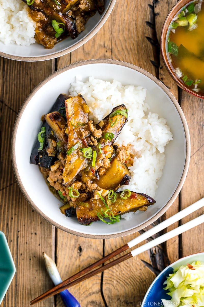 A white bowl containing Mapo Eggplant (Mabo Nasu) served over steamed rice.