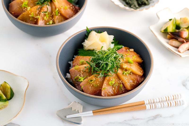 A ceramic bowl containing miso marinated hamachi served on bed of steamed rice along with shiso, scallion, and sushi ginger.