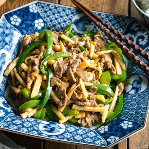 A Japanese blue and white ceramic containing Beef and Green Pepper Stir Fry.