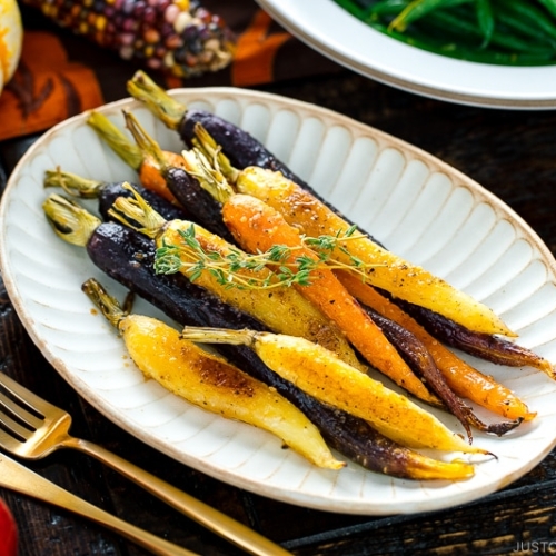 A white ceramic plate containing Maple and Miso Glazed Roasted Carrots.