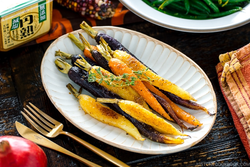 A white ceramic plate containing Maple and Miso Glazed Roasted Carrots.