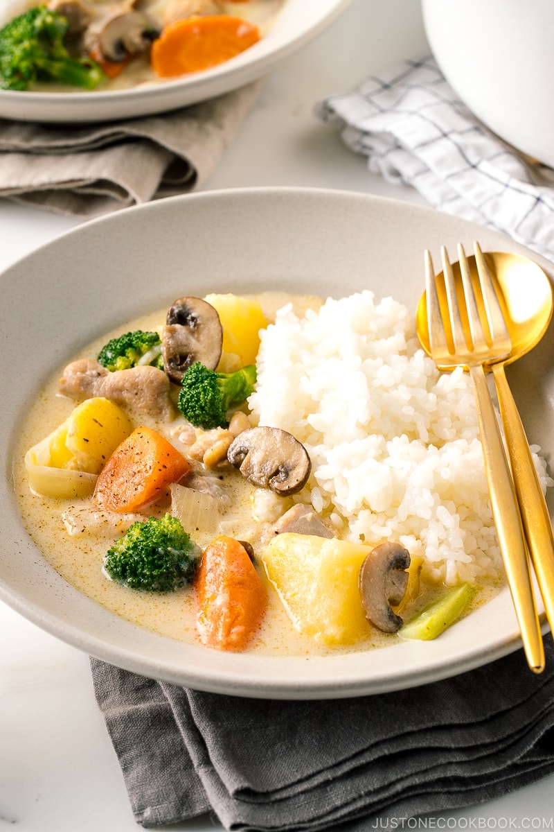 A beige ceramic dish containing steamed rice and Japanese cream stew.