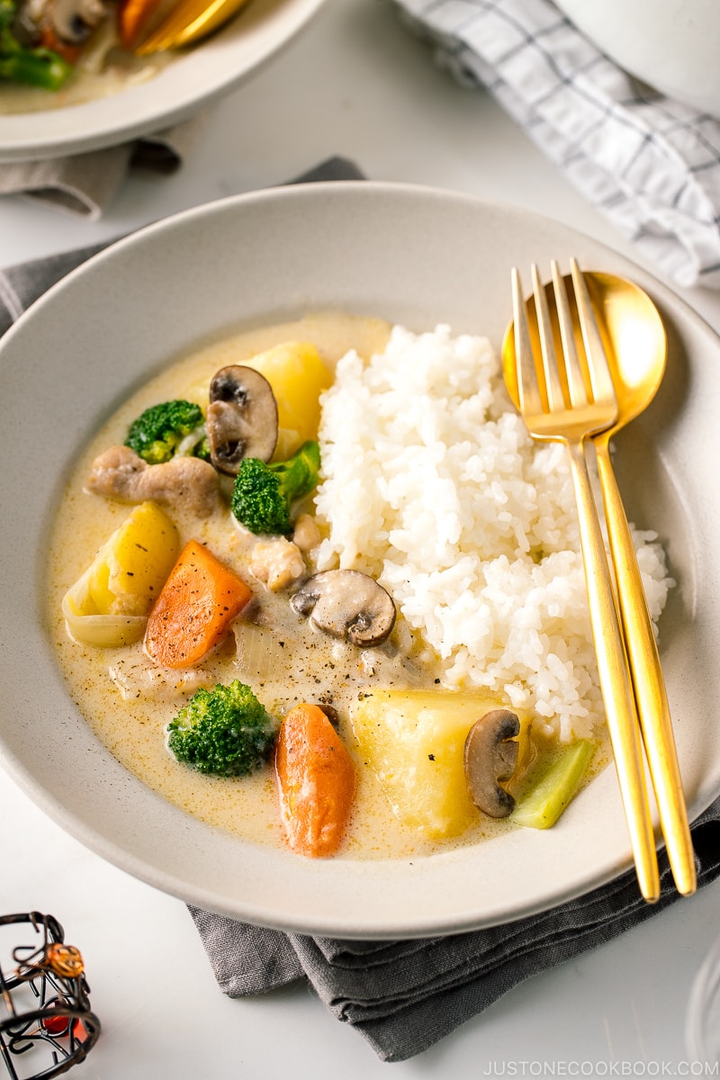 A beige ceramic dish containing steamed rice and Japanese cream stew.